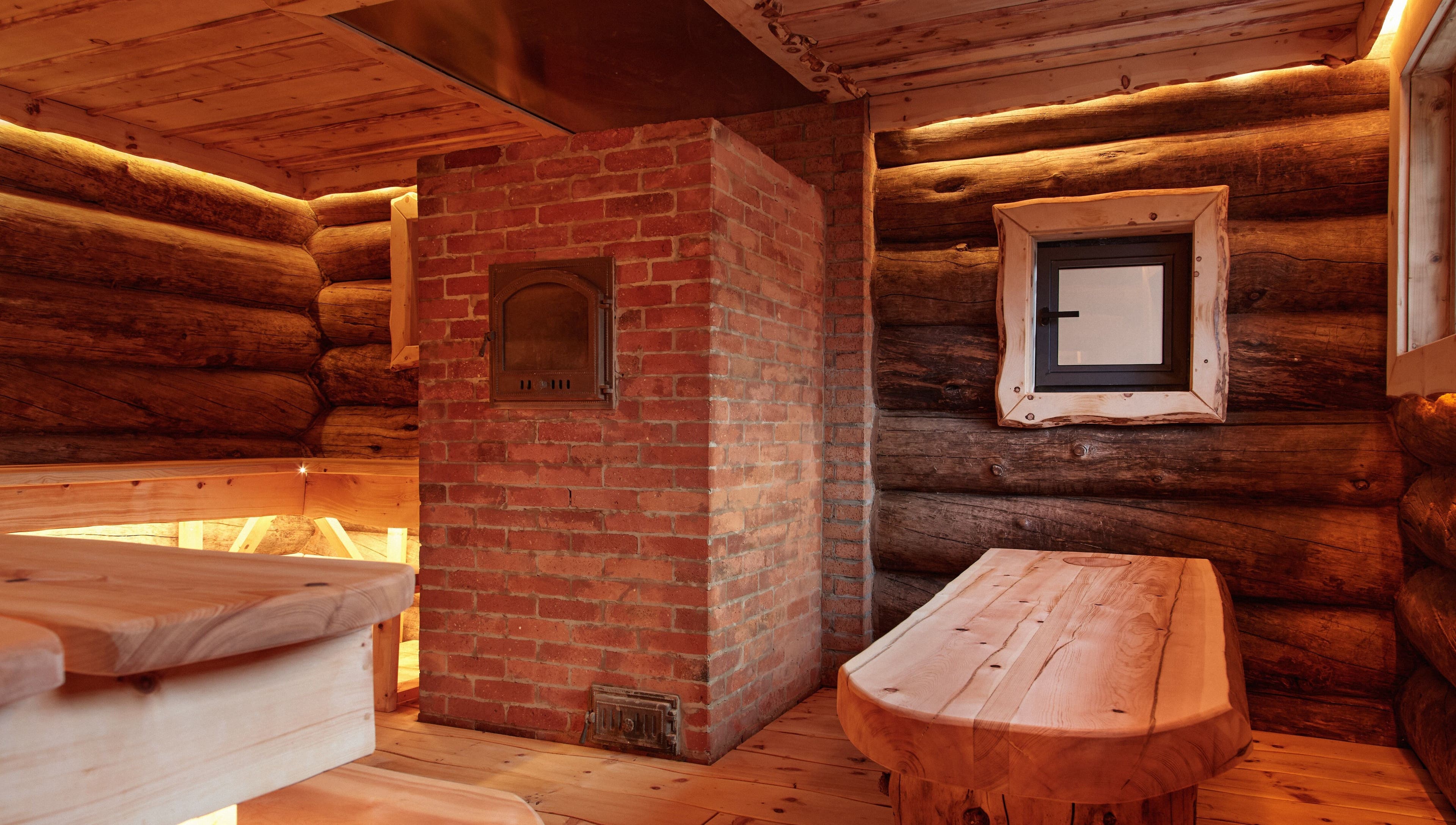 Cozy wooden sauna interior at Banya No.1 Tbilisi Private in Kiketi, GE, with brick oven and warm lighting.