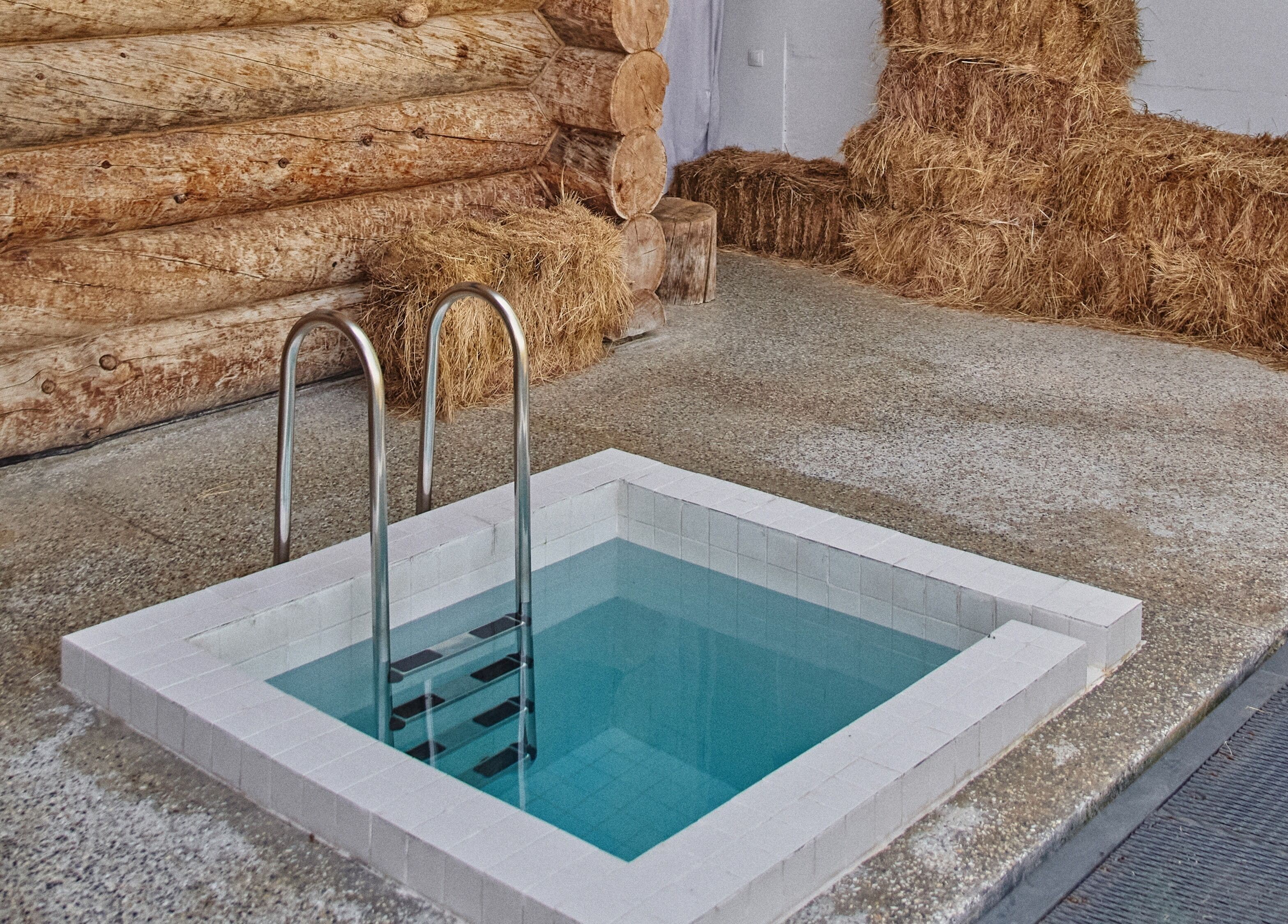 Private pool area at Banya No.1 Tbilisi Private, Kiketi, GE with wooden log walls and hay accents.