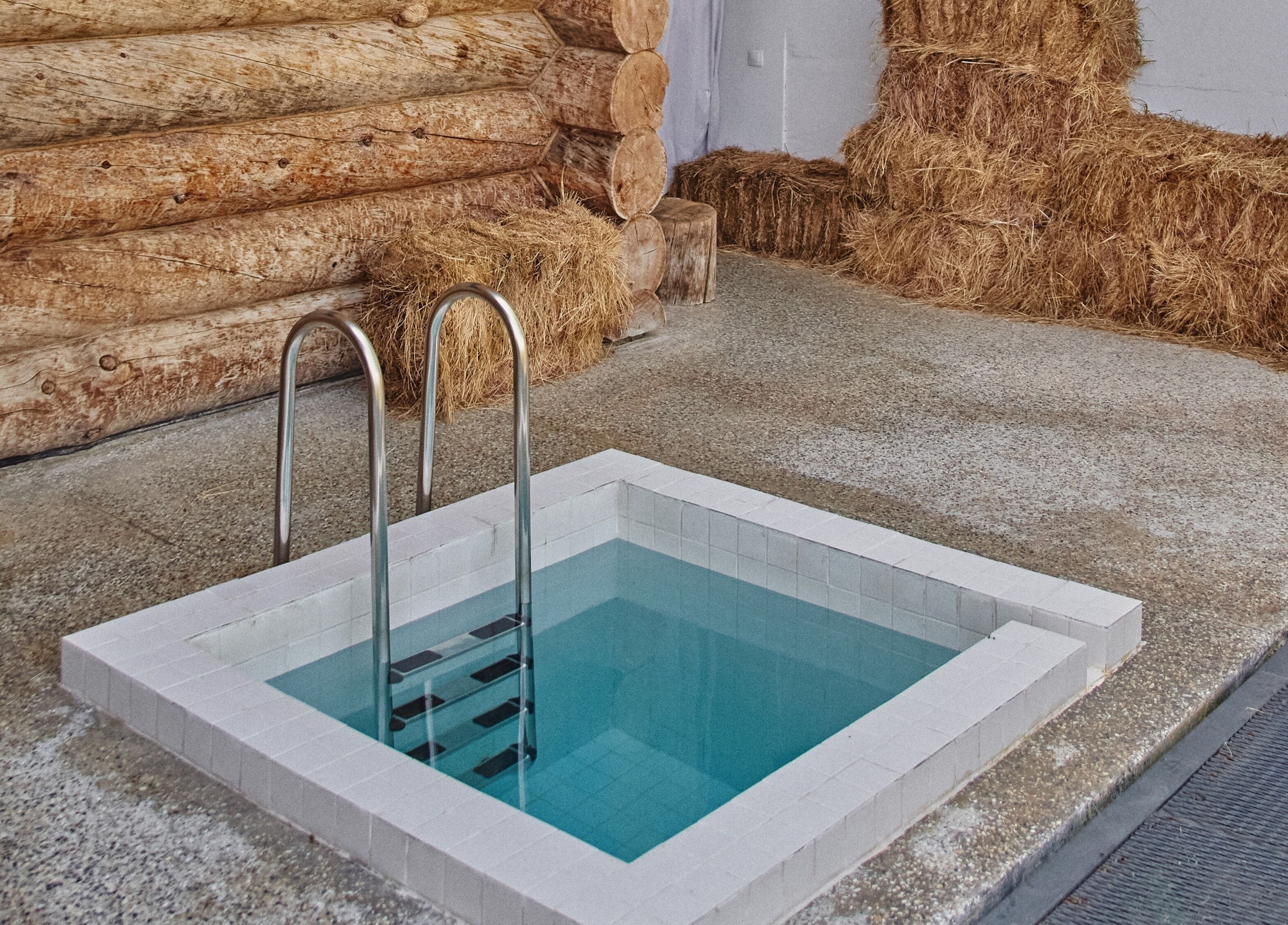 Private pool area at Banya No.1 Tbilisi Private, Kiketi, GE with wooden log walls and hay accents.