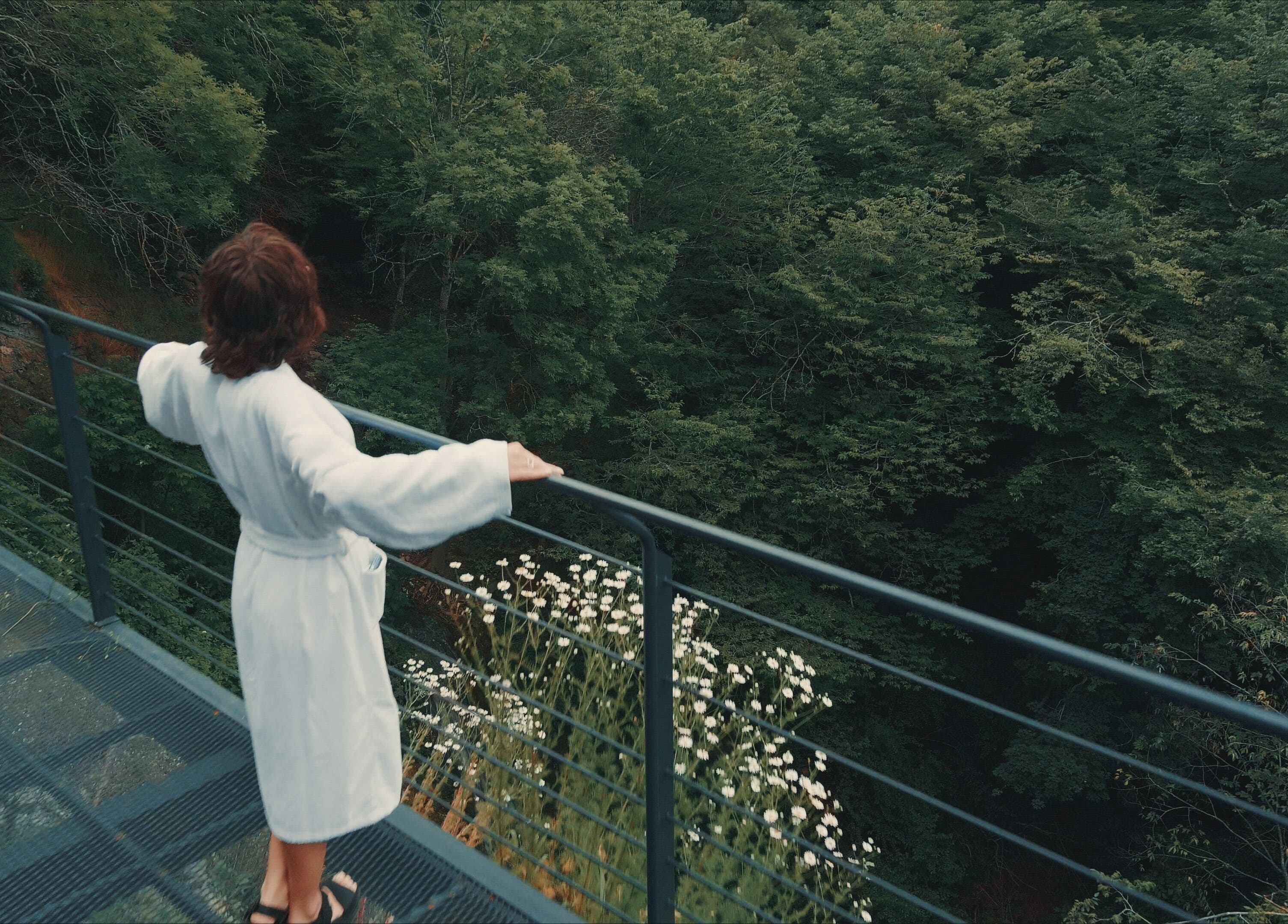 Relaxation at Banya No.1 Tbilisi Private, Kiketi, GE. Person in robe enjoys forest view.