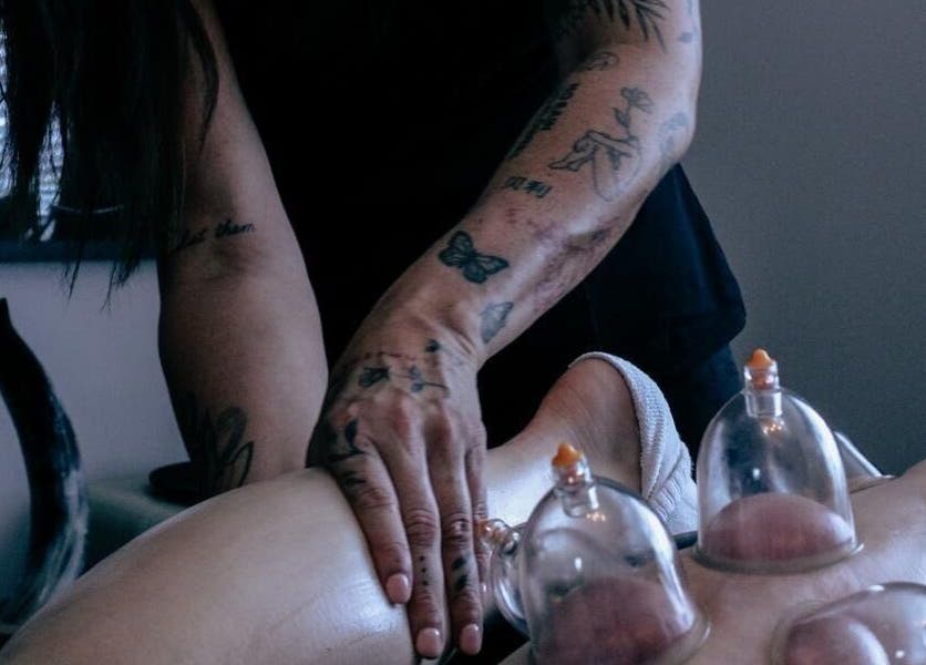 Cupping therapy in progress at Keep Moving Forward, Dumfries, Scotland, GB. Tattooed hand applying cups.