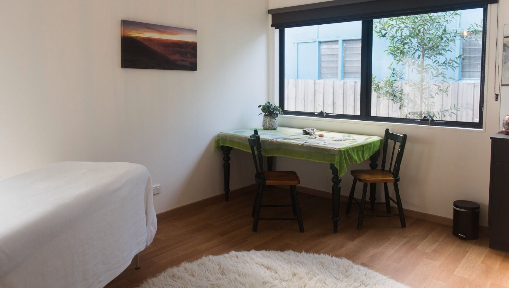 Bright, cozy room at Wildheart Healing, Cygnet, Tasmania, AU with table, chairs, and massage bed.
