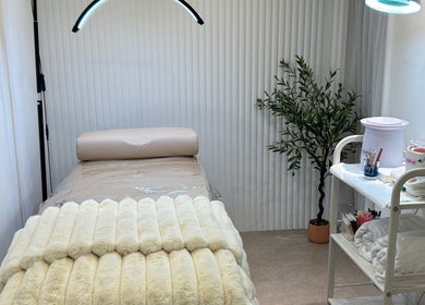 Tranquil treatment room at Houseofbeauty, London, England, GB with cozy bed and plant for relaxation.