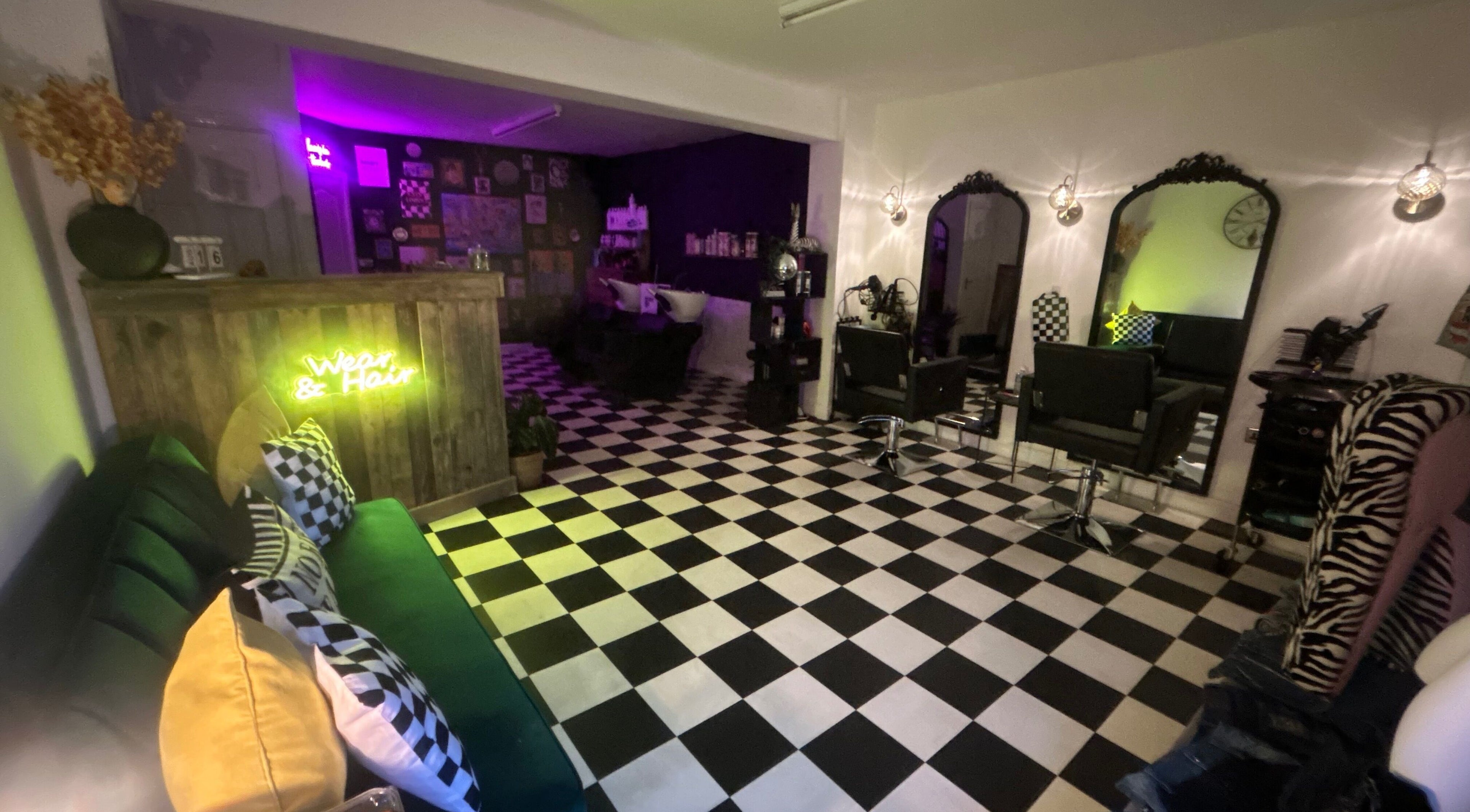 Stylish salon interior at Wear and Hair, Tyldesley, England with chic black and white decor and neon accents.