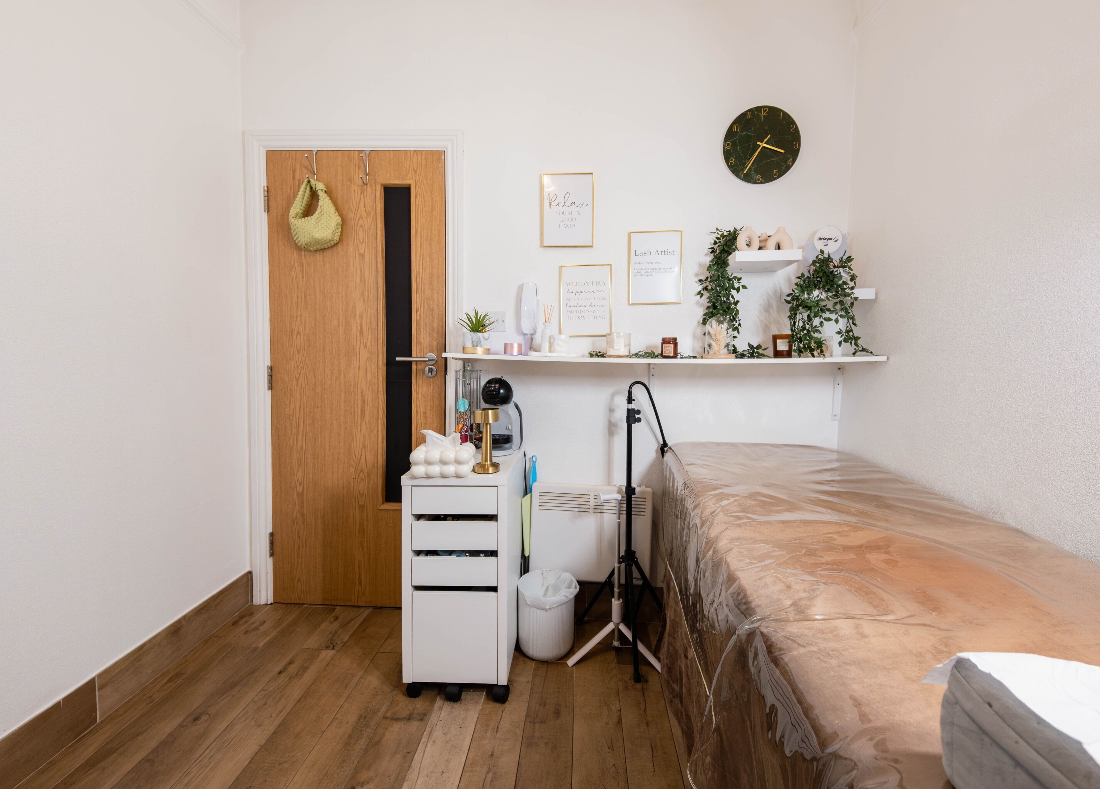 Cozy treatment room at Arieyes, London, England with decor, shelves, and a treatment table.