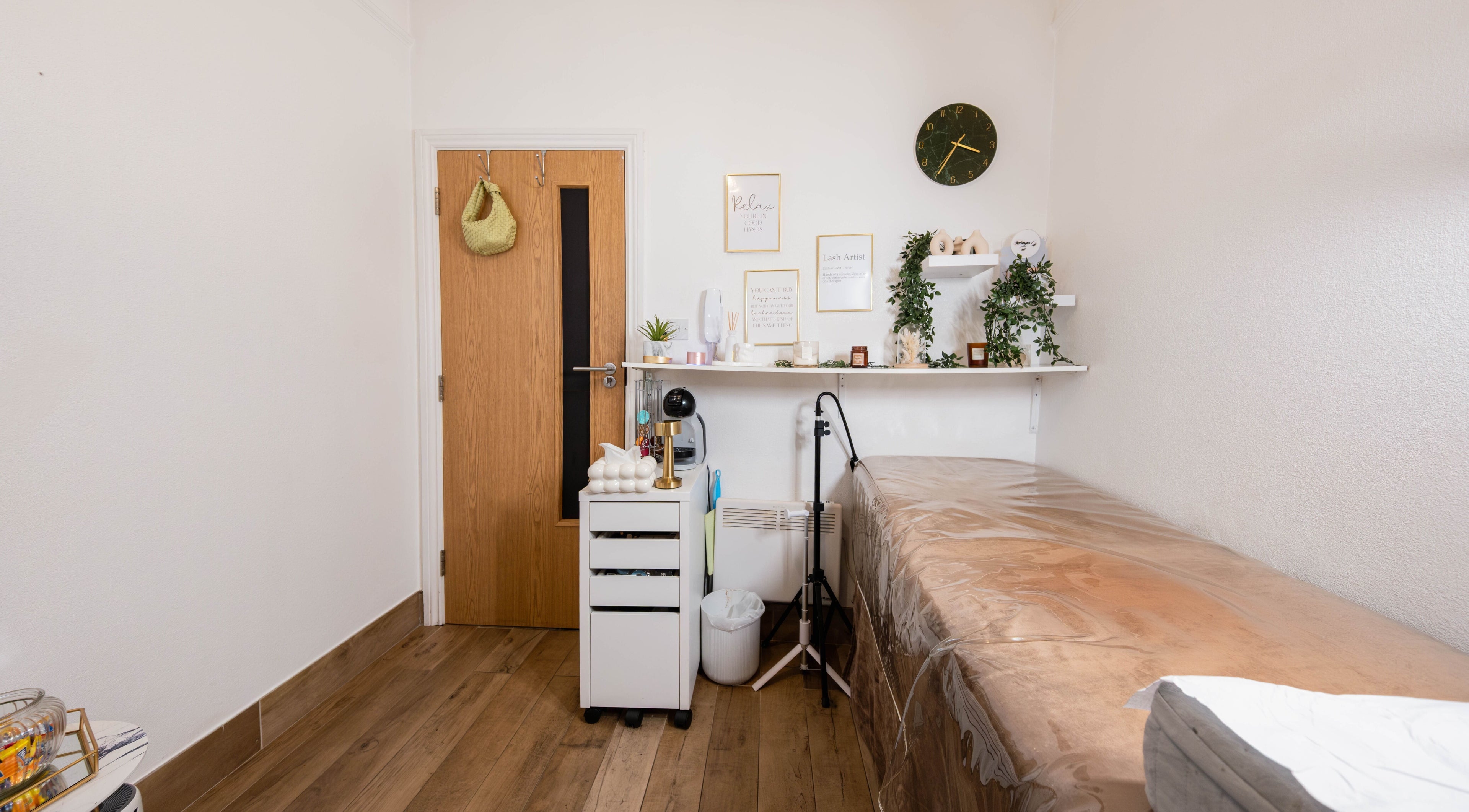 Cozy treatment room at Arieyes, London, England with decor, shelves, and a treatment table.
