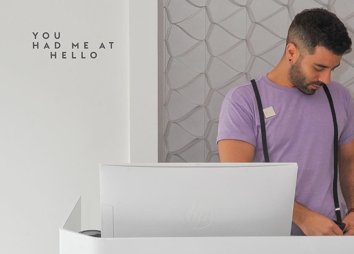 Reception desk at UNOIT Barber in Darlinghurst, New South Wales with a welcoming message on the wall.