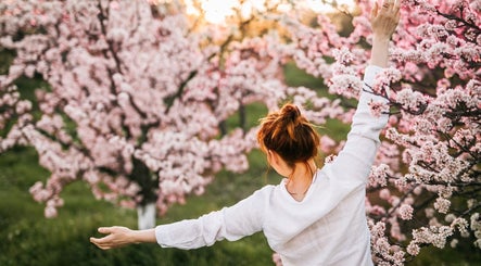 Woman enjoying cherry blossoms at Vixi Wellbeing Hub, Darlington, England, GB. Embrace nature's tranquility.