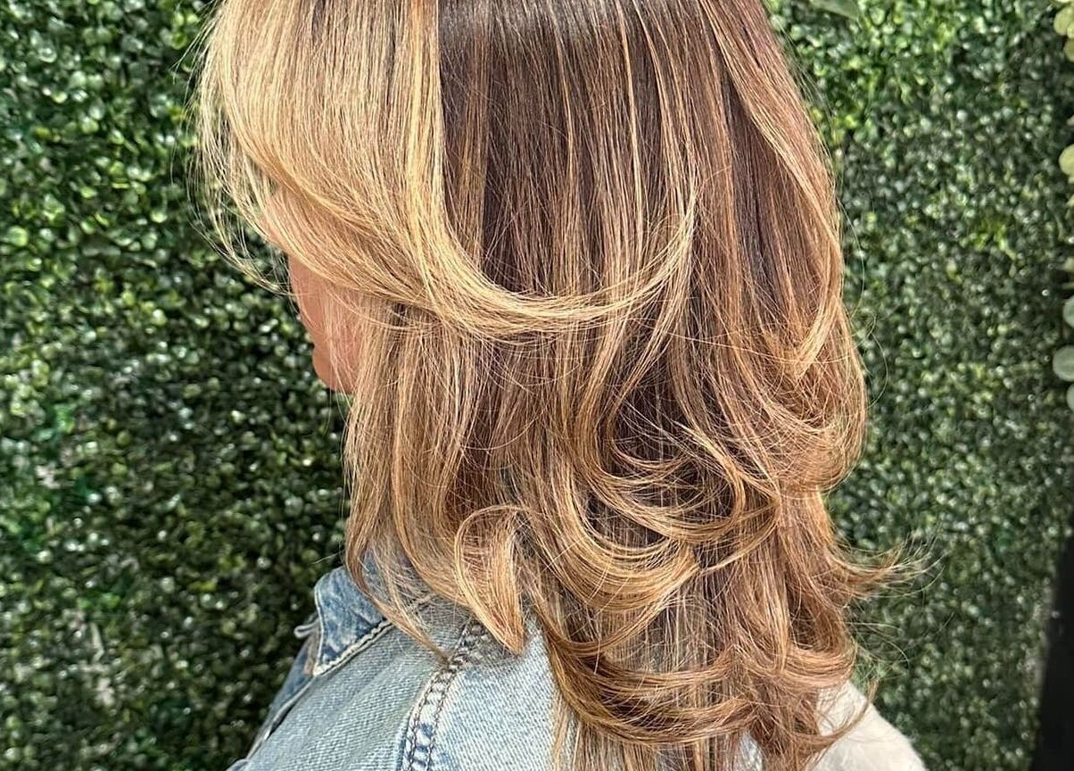 Beautiful layered hairstyle at Concept Dominican Hair Studio, West Palm Beach, Florida, US, on a green backdrop.