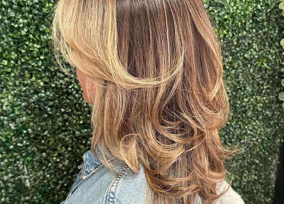 Beautiful layered hairstyle at Concept Dominican Hair Studio, West Palm Beach, Florida, US, on a green backdrop.