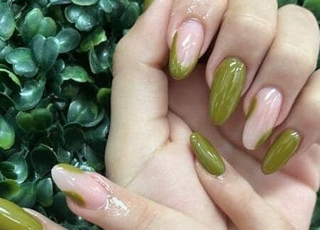 Green manicure on display at Concept Dominican Hair Studio, West Palm Beach, Florida, US with leafy background.