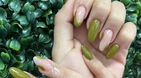 Green manicure on display at Concept Dominican Hair Studio, West Palm Beach, Florida, US with leafy background.