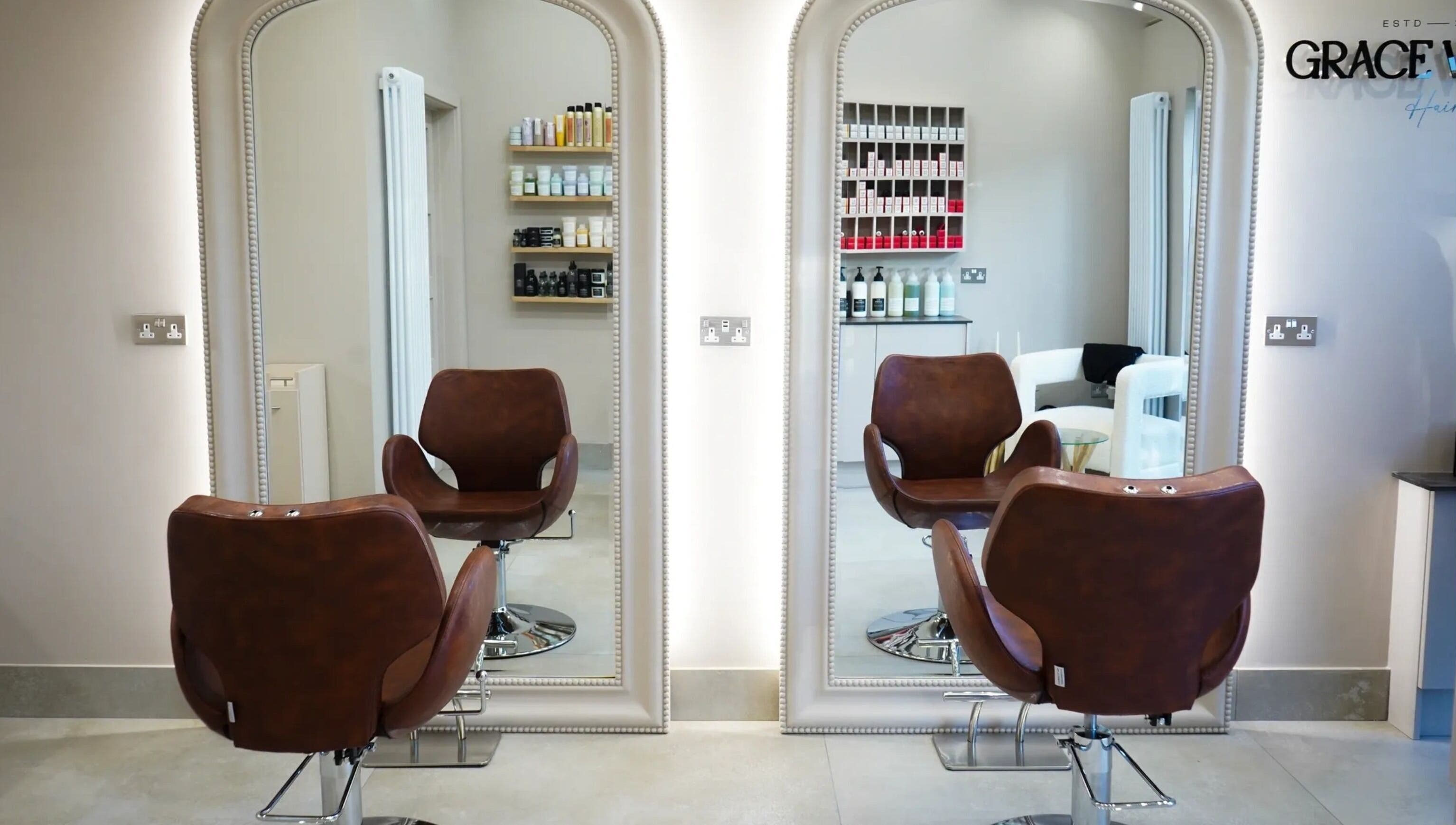 Stylish salon chairs facing mirrors at Grace Waker Hair in Oakley, England, GB with hair products displayed.