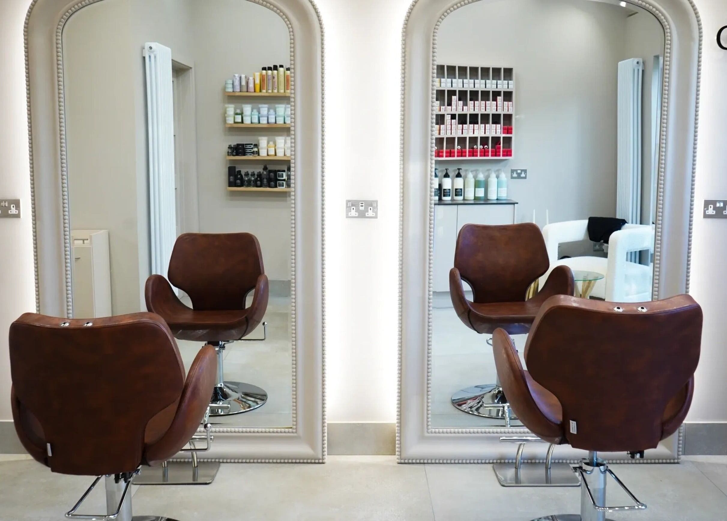 Stylish salon chairs facing mirrors at Grace Waker Hair in Oakley, England, GB with hair products displayed.