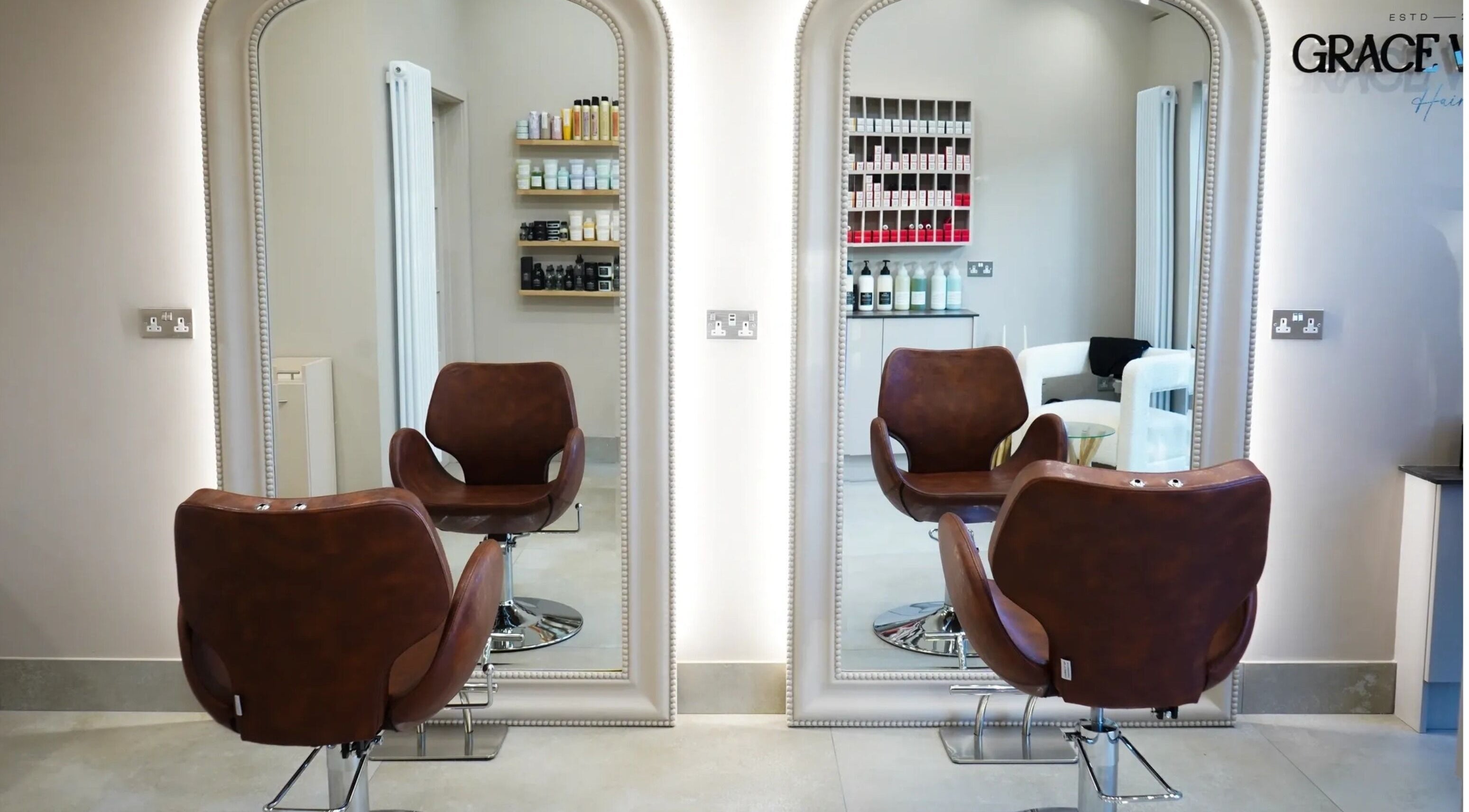 Stylish salon chairs facing mirrors at Grace Waker Hair in Oakley, England, GB with hair products displayed.