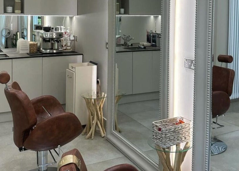 Stylish salon interior at Grace Waker Hair in Oakley, England, GB, featuring cozy brown chairs and modern decor.