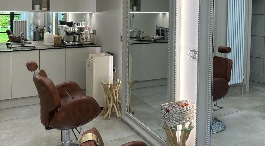 Stylish salon interior at Grace Waker Hair in Oakley, England, GB, featuring cozy brown chairs and modern decor.