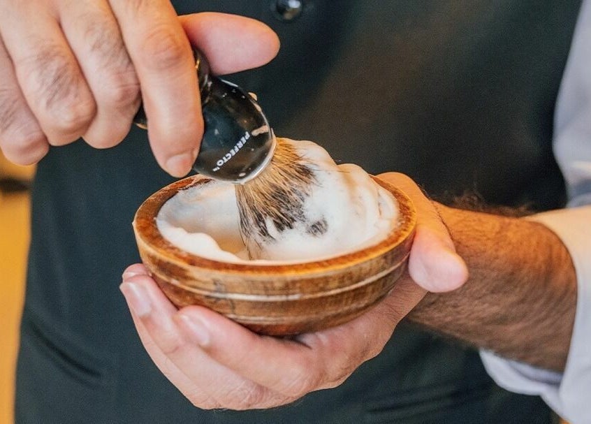 Shaving brush in lather at The Groom Room - Riffa Views, Al Mazrowiah, BH, perfecting grooming rituals.
