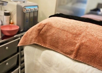 Acenti Skin spa bed with peach towel in London, England, GB, ready for a relaxing session.