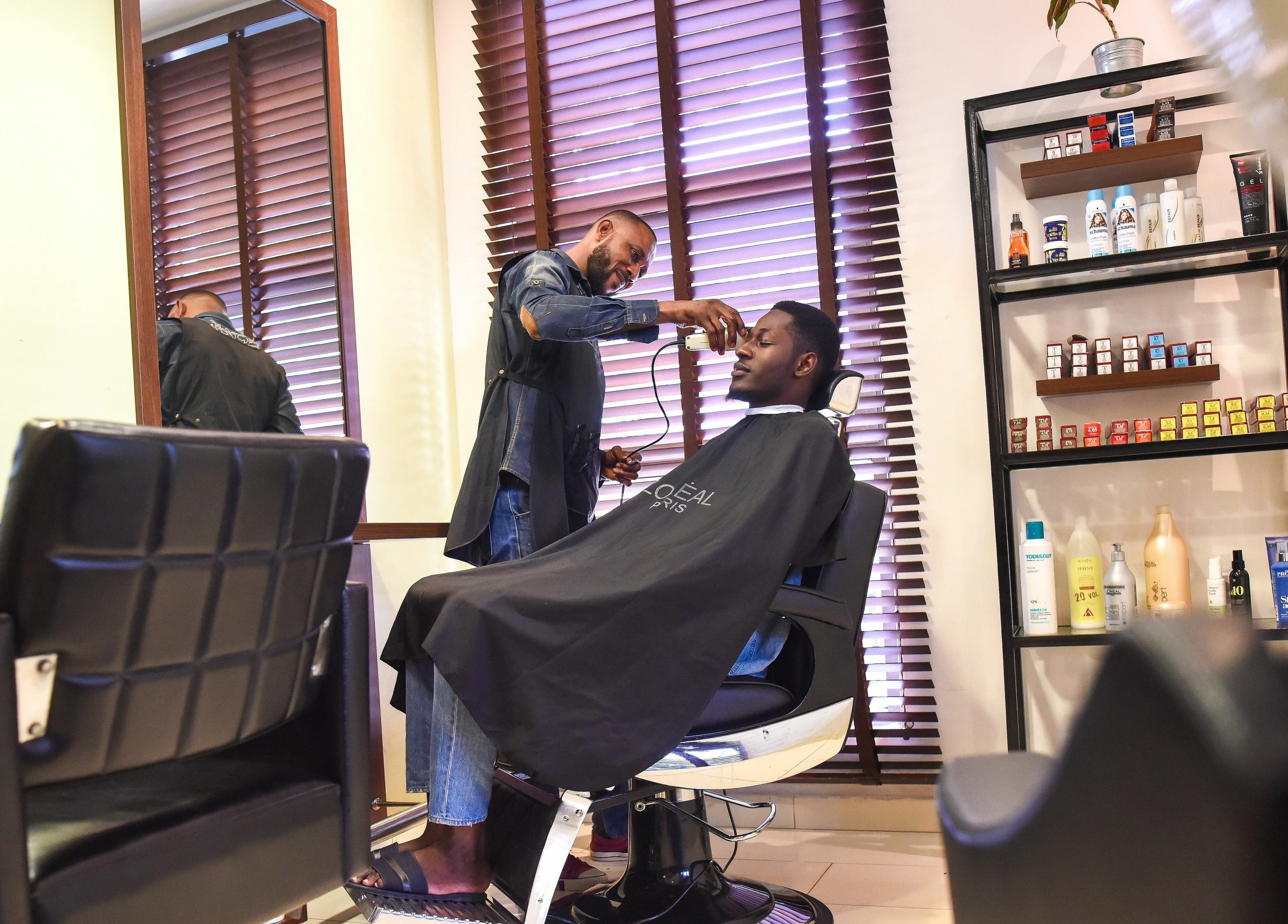 Barber styling a client's hair at Beauty Addict, Abuja, Federal Capital Territory, NG.