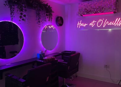 Modern salon interior at Hair at O’Neills, Fareham. Illuminated vanity mirrors enhance the stylish ambiance.