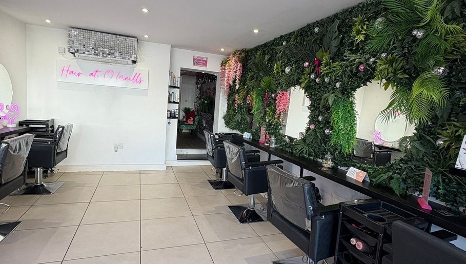 Stylish salon interior at Hair at O'Neills, Fareham, England with green decor and modern chairs.