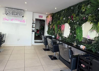 Stylish salon interior at Hair at O'Neills, Fareham, England with green decor and modern chairs.