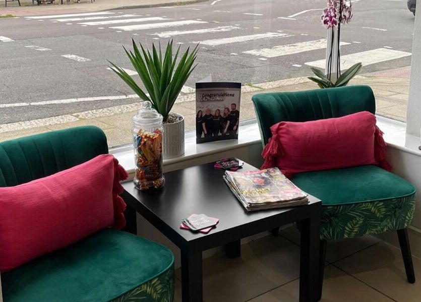 Inviting seating area at Hair at O’Neills, Fareham, England, GB with green chairs and pink cushions.