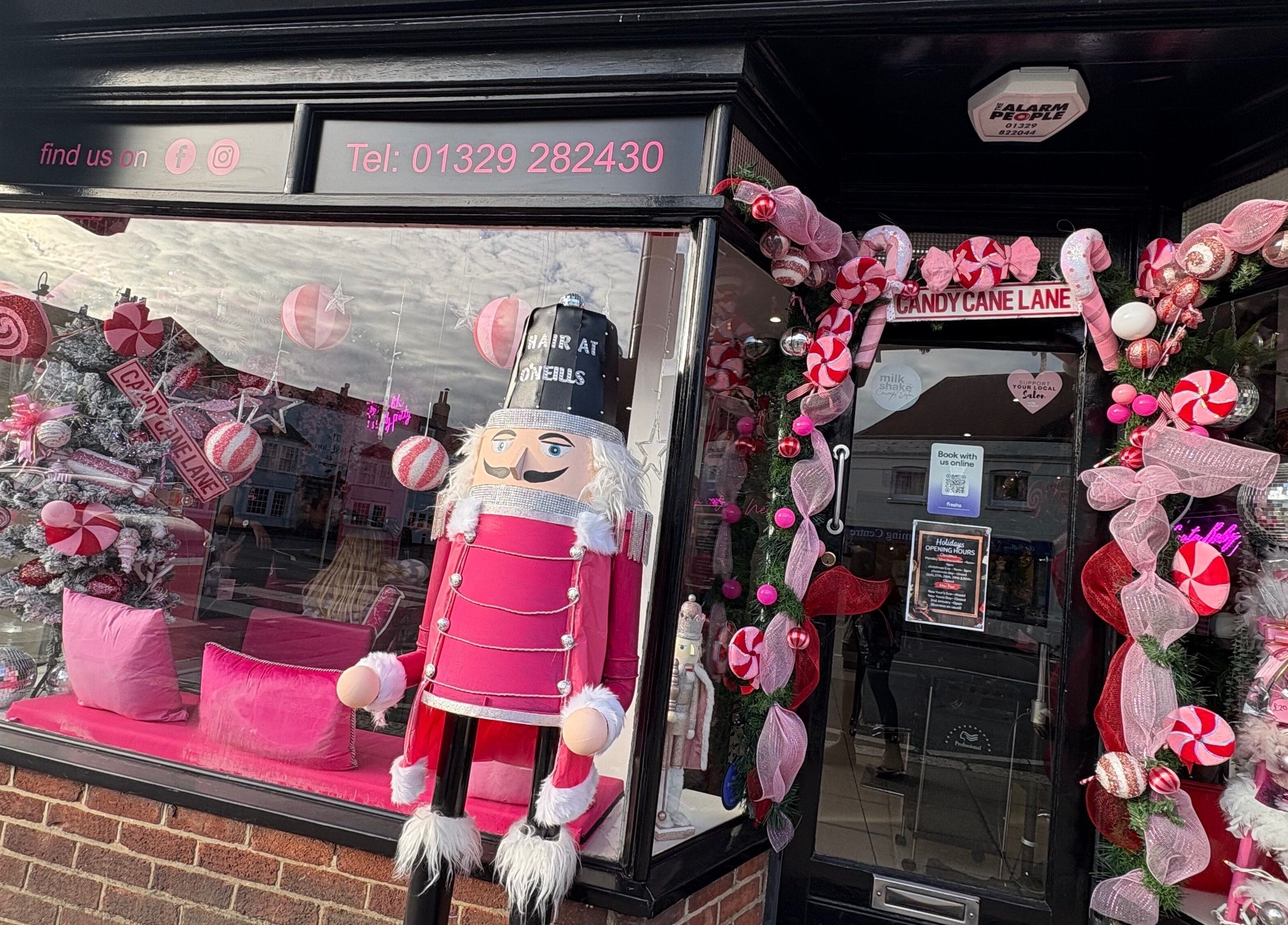 Festive storefront at Hair at O’Neills, Fareham, England, GB, with holiday decorations and nutcracker display.