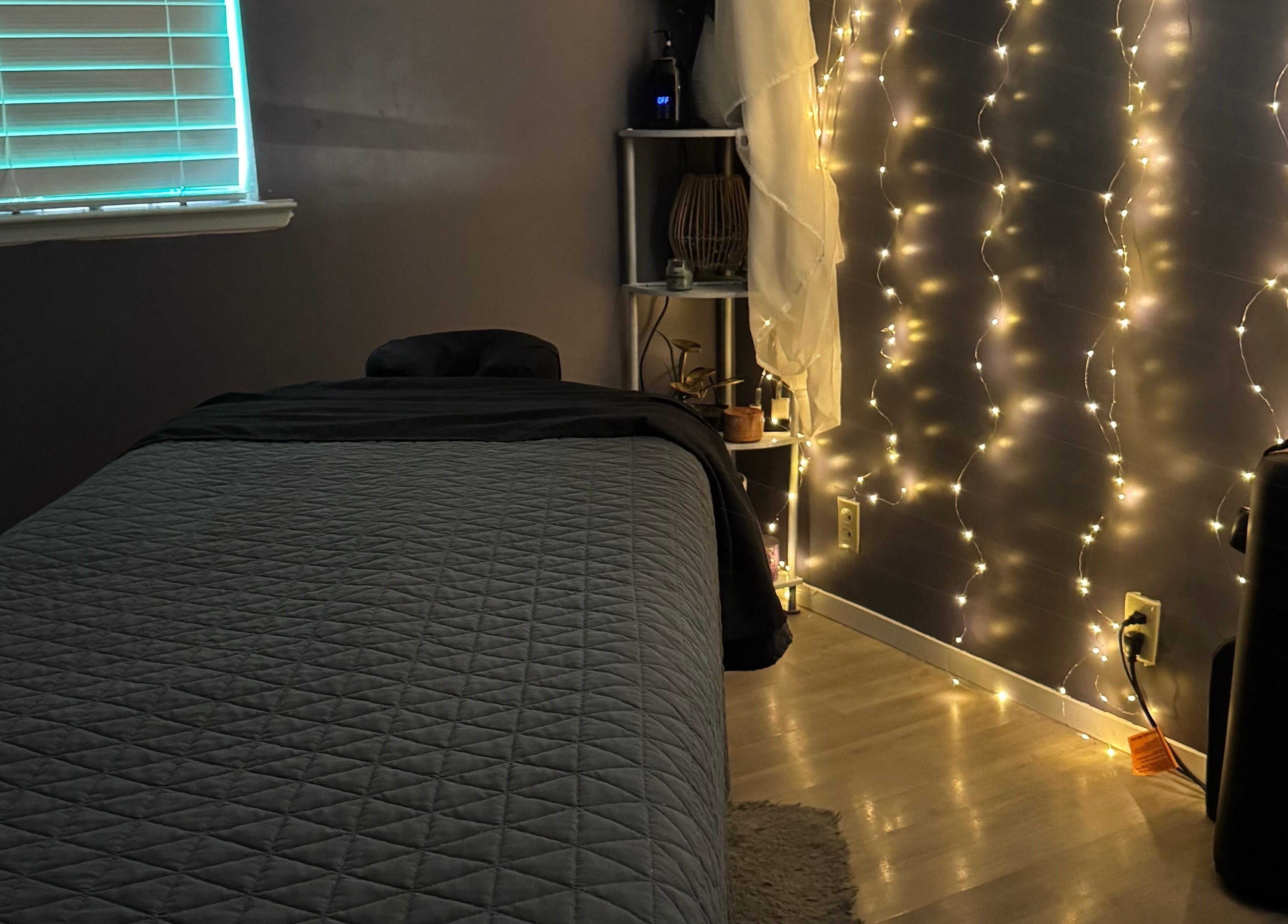 Tranquil massage room at Hands on Healing, Coalinga, California, US, softly illuminated by string lights.