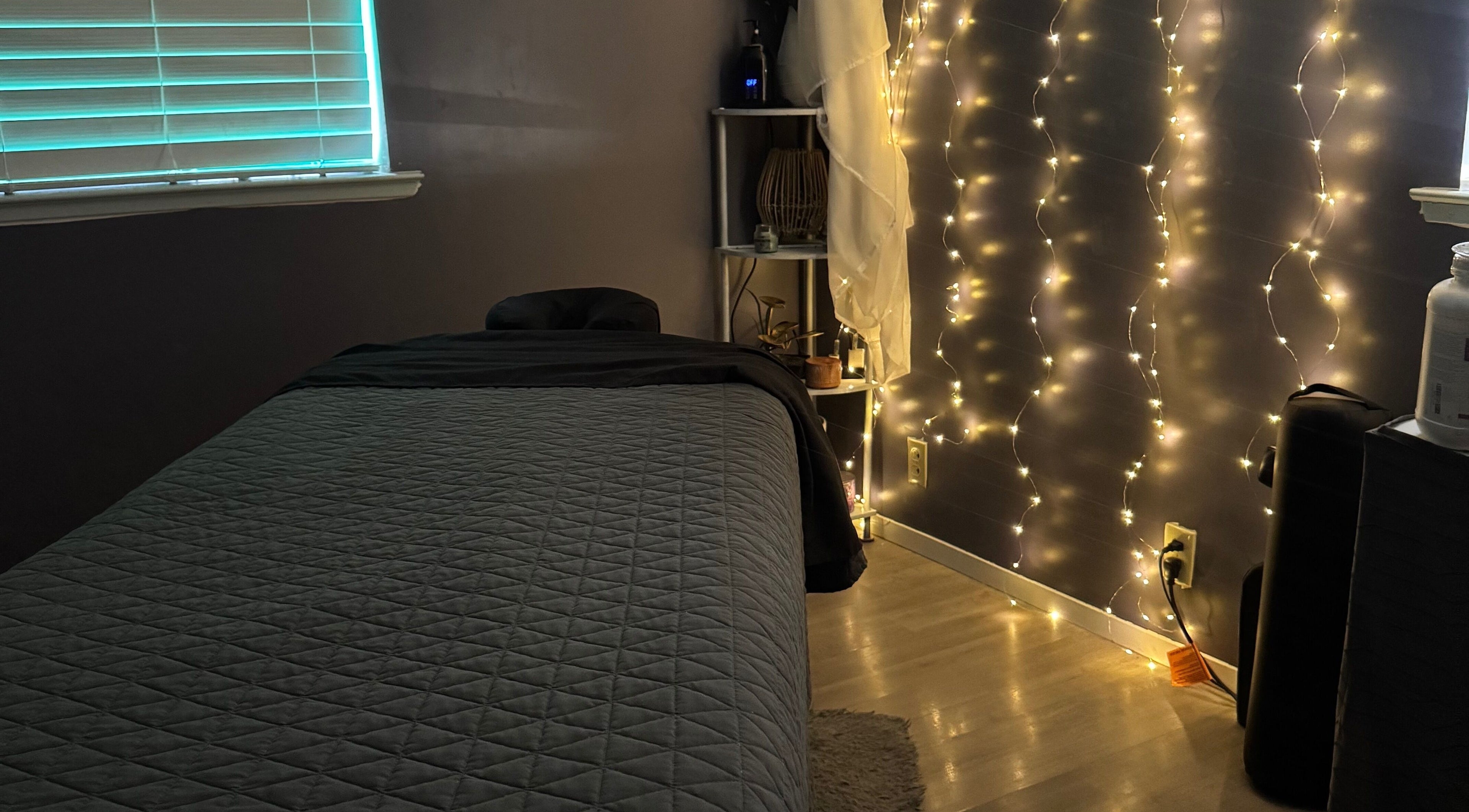 Tranquil massage room at Hands on Healing, Coalinga, California, US, softly illuminated by string lights.