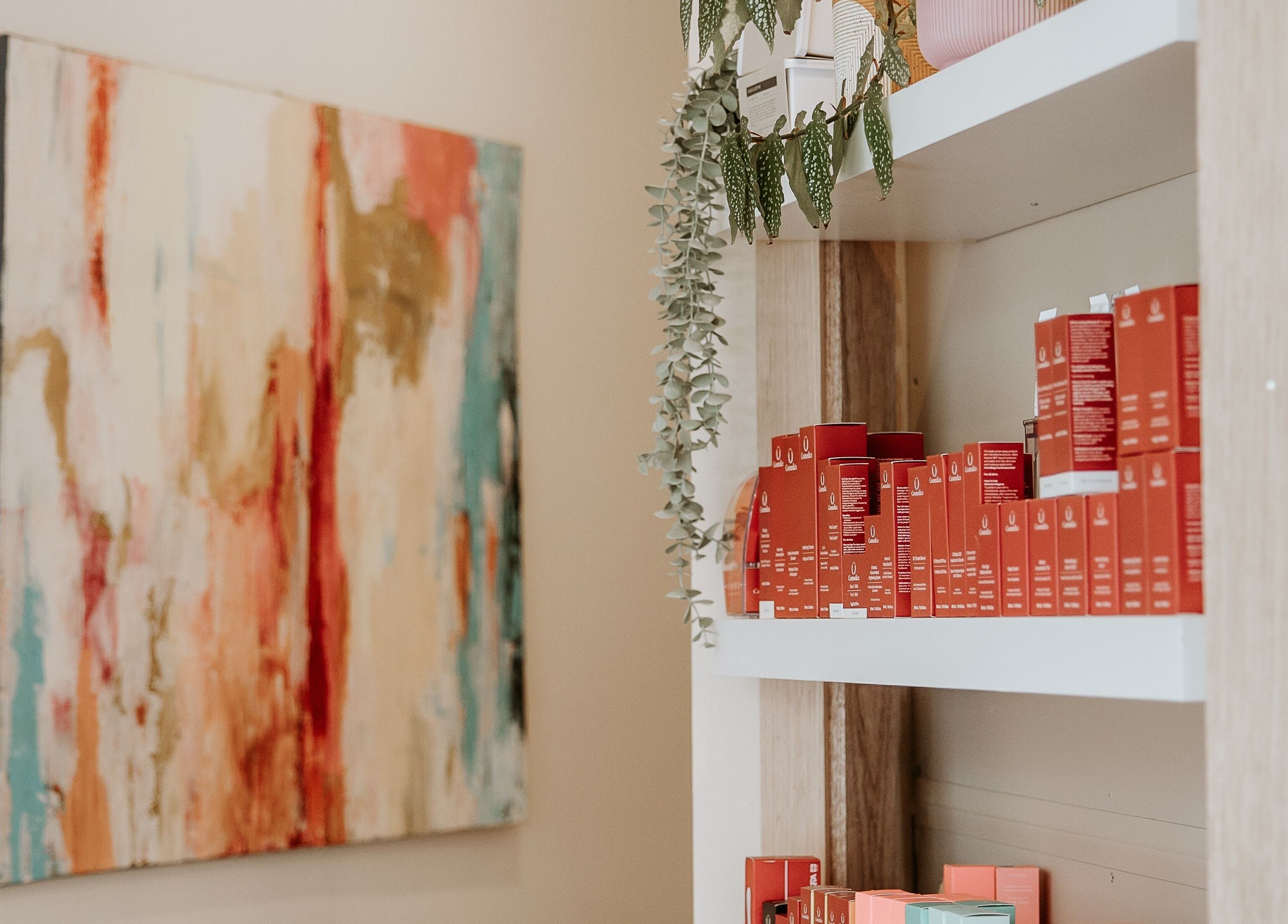 Vibrant products on shelves at Your Skin Room, Melbourne, Victoria, AU with abstract art in the background.