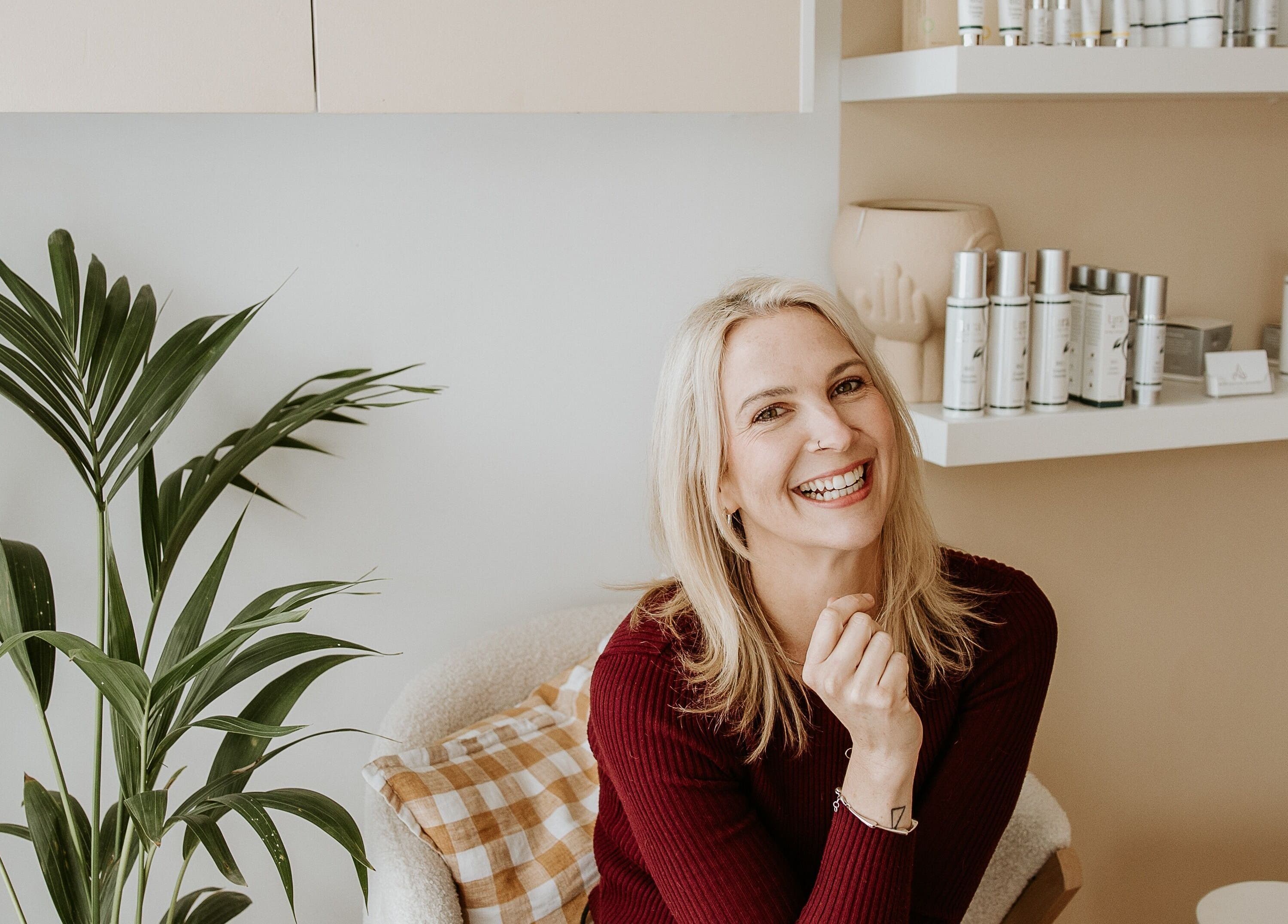 Smiling woman at Your Skin Room, Melbourne, Victoria, AU surrounded by skincare products.