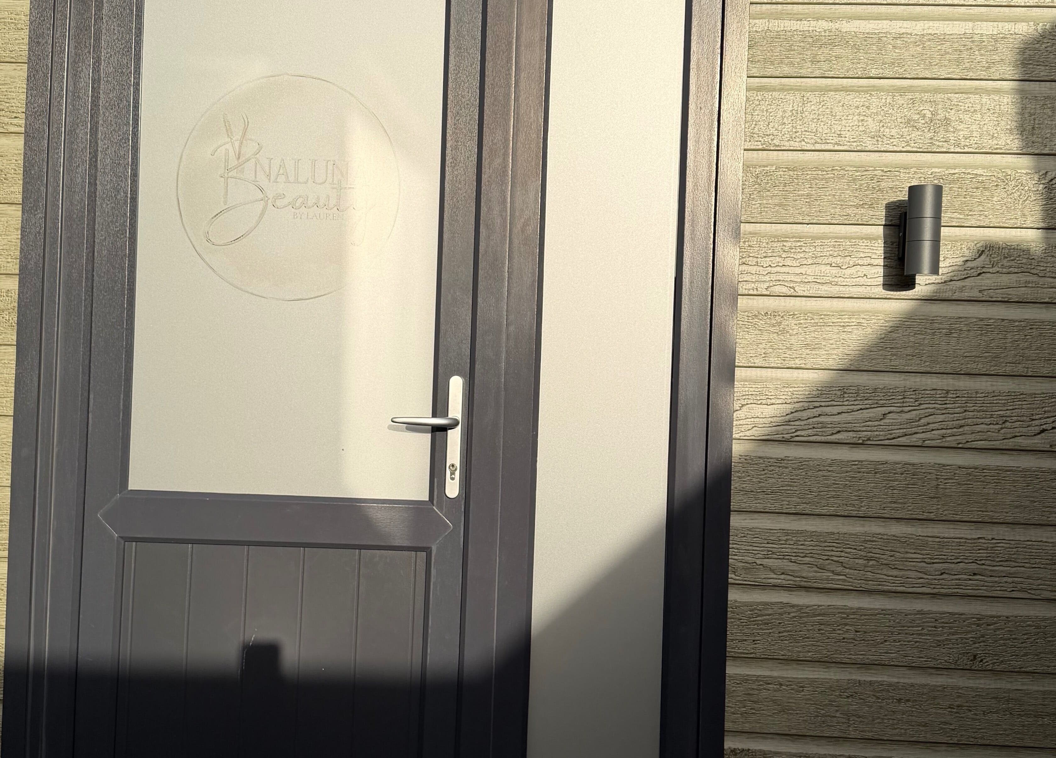 Front door of Naluna Beauty by Lauren in Garforth, England, GB with stylish wooden panel.