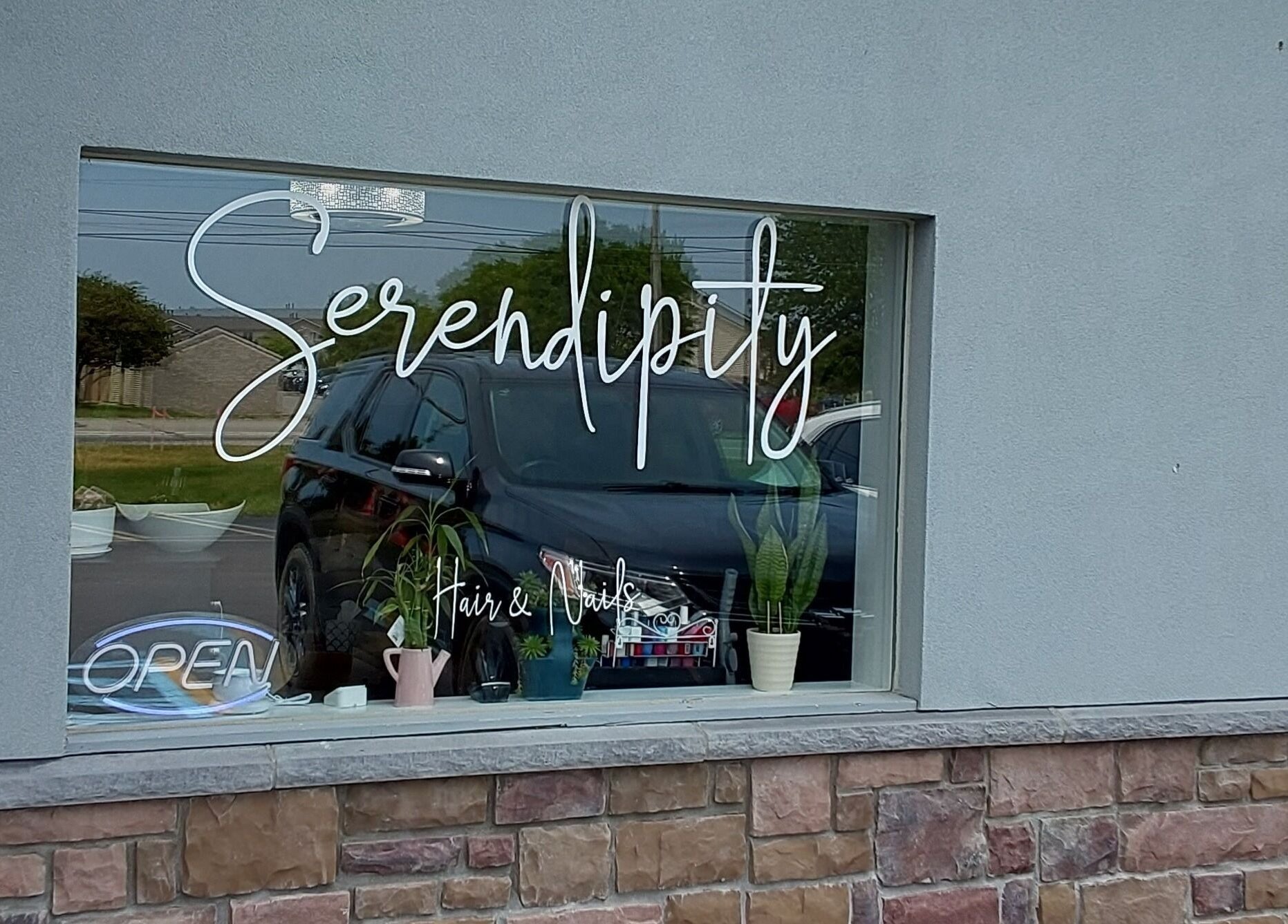 Front window of Serendipity Hair and Nails in Davison, Michigan, US with signage and plants.