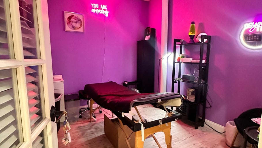 Cozy purple treatment room at Lemmey Esthetics, Addison, Texas, US, featuring a massage table and neon lights.
