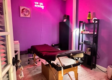 Cozy purple treatment room at Lemmey Esthetics, Addison, Texas, US, featuring a massage table and neon lights.