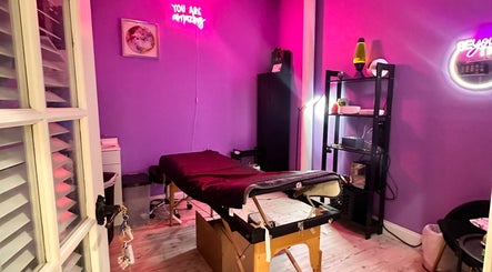 Cozy purple treatment room at Lemmey Esthetics, Addison, Texas, US, featuring a massage table and neon lights.