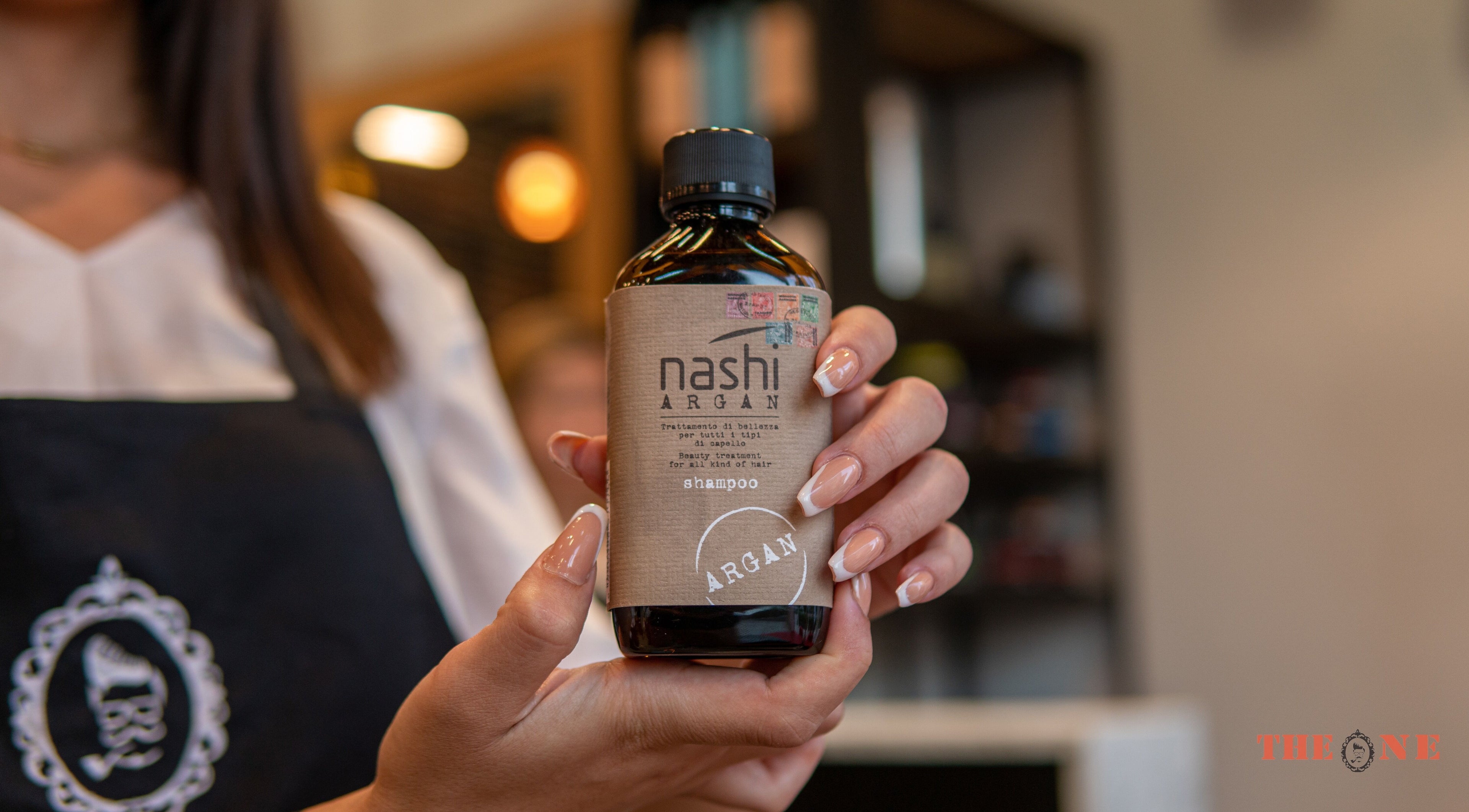 Woman presenting Nashi Argan shampoo at The One Gents Salon (Tecom Branch), Dubai, Dubai, AE.