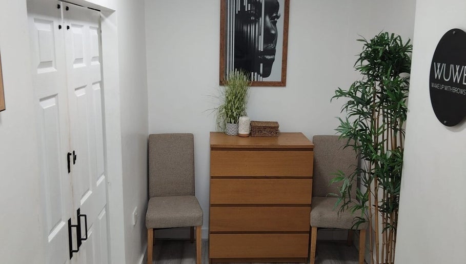 Relaxed waiting area at Wake Up With Brows UK, London, GB. Features cozy chairs and decorative plants.