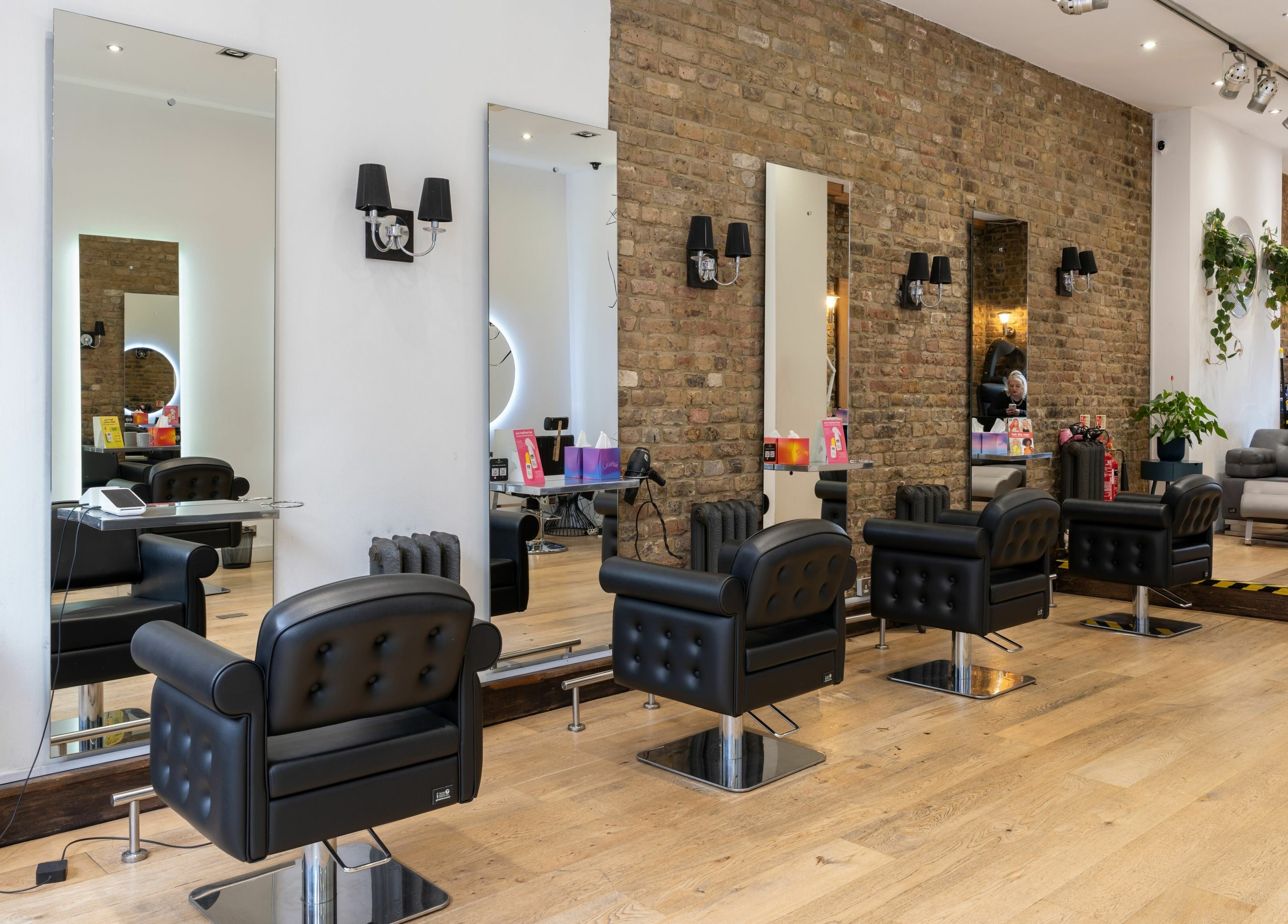 Elegant interior of Chelsea Chair salon in London, England, GB with sleek styling stations and brick walls.