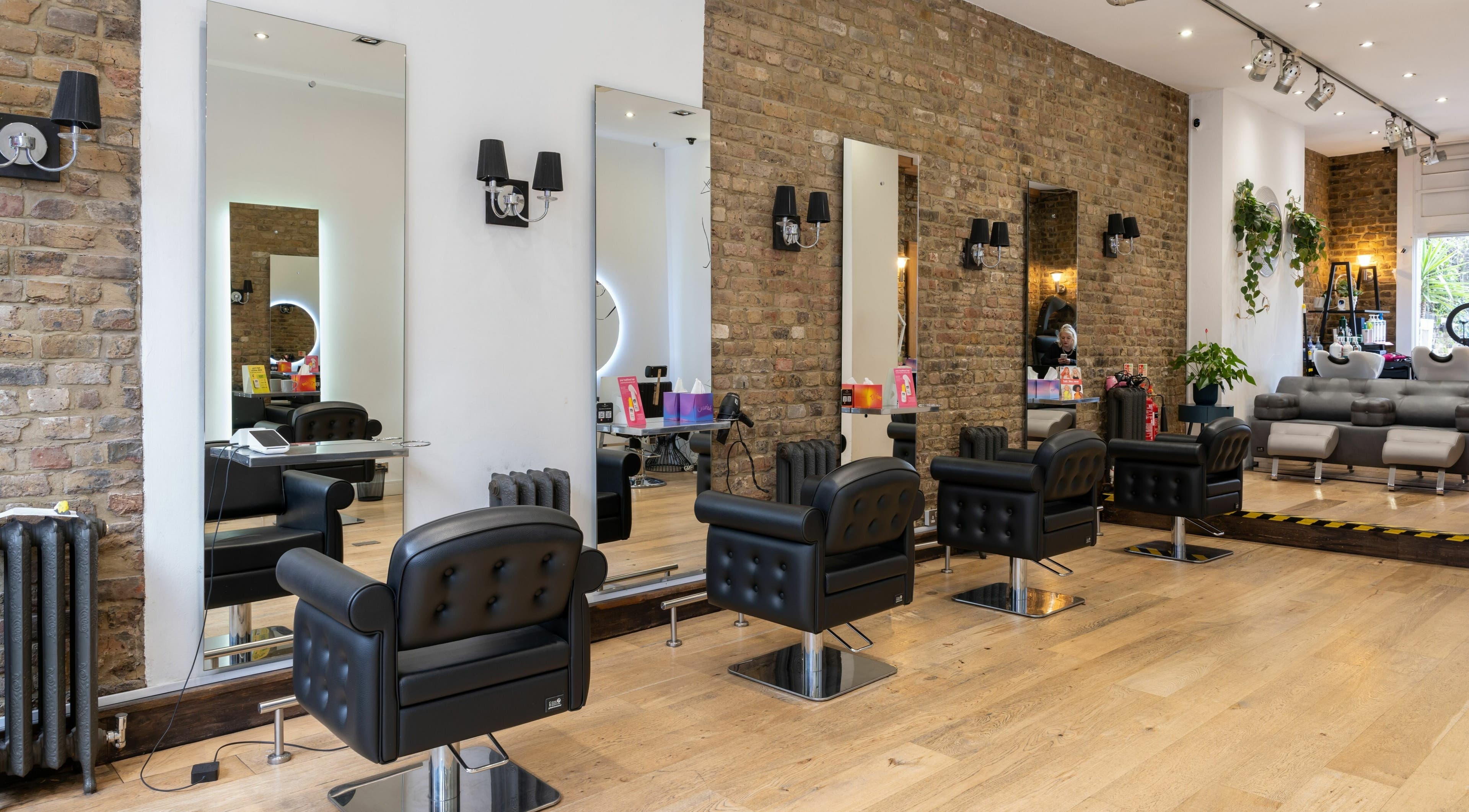 Elegant interior of Chelsea Chair salon in London, England, GB with sleek styling stations and brick walls.