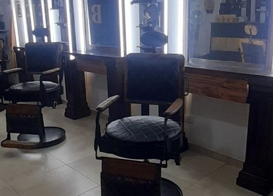 Interior de Sir Barber en Moron, Provincia de Buenos Aires, AR, con sillas y espejos iluminados.