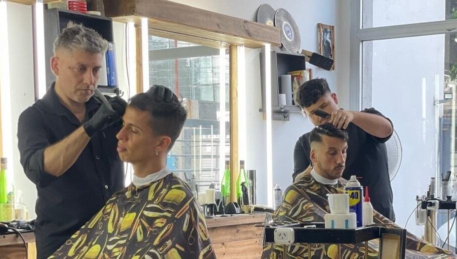 Dos barberos de SIR BARBER en Morón, Provincia de Buenos Aires, AR, cortando cabello con precisión.
