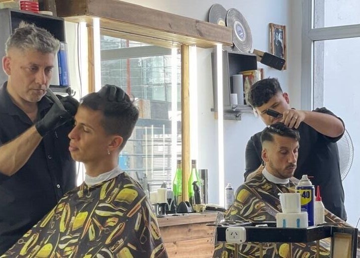 Dos barberos de SIR BARBER en Morón, Provincia de Buenos Aires, AR, cortando cabello con precisión.