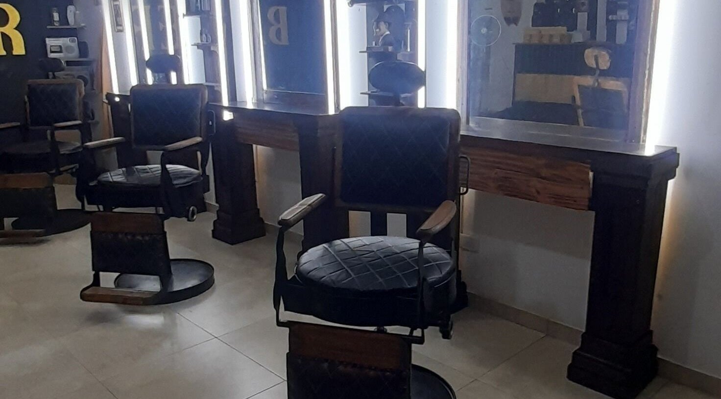 Interior de SIR BARBER en Morón, Provincia de Buenos Aires, mostrando sillas y espejos iluminados.