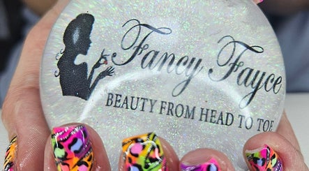 Close-up of vibrant nail art holding Fancy Fayce logo orb at beauty venue in Huddersfield, England, GB.