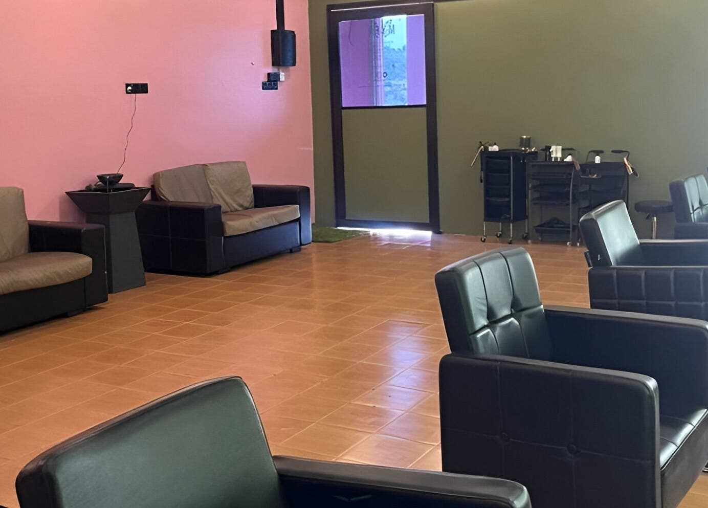 Modern seating area of Myfa Salon Indera Makhota 15, Indera Mahkota, Pahang, MY with plush black chairs and pink walls.
