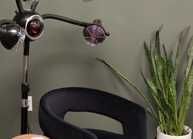 Stylish corner at Unorthodox Salon, Taylors, SC, featuring a black chair, modern lamp, and snake plant.