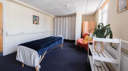 Mara Nicola (Somatics & Bodywork) therapy room in London, England, GB features a massage table and cozy seating.
